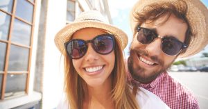 young white couple smiling & wearing sunglasses